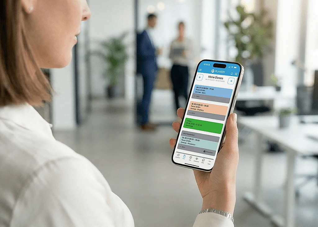 Weibliche Person mit Smartphone in der Hand im Büro. Planery Dienstplan ist geöffnet 